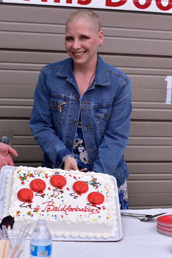 Erin Hansman poses for a picture with a cake with the message #baldforbabies on it. Photo courtesy of Eastside Baby Corner