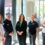 Representatives from the city, police department and Bank of America on Northeast 4th Street gather to put up the Safe Place Program signs and stickers in the front window. Evan Pappas/staff photo
