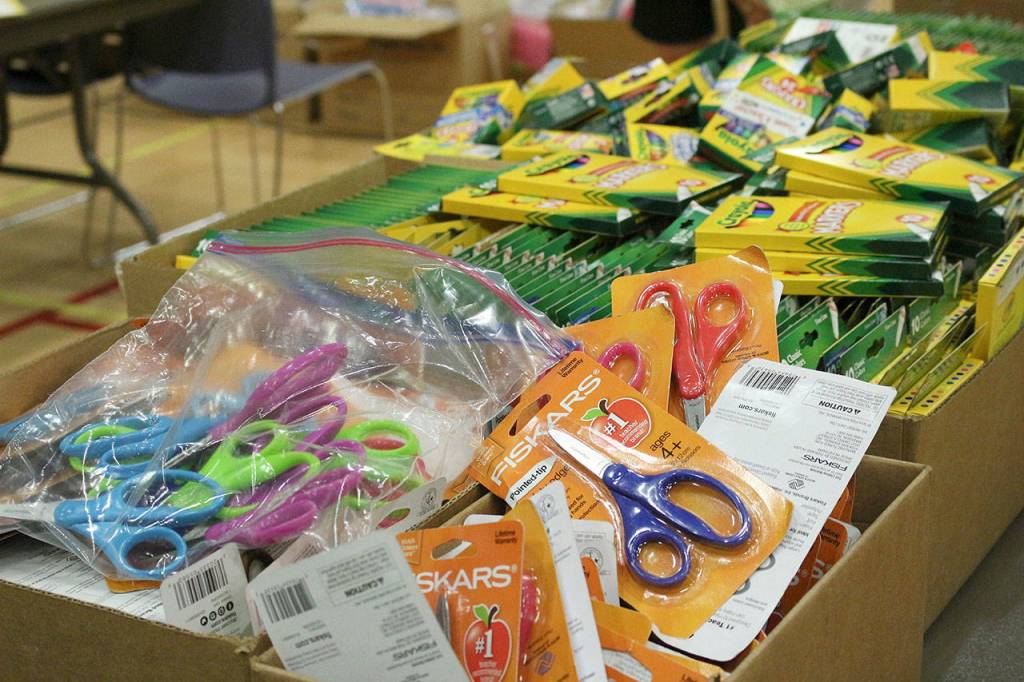 Table of school supplies waiting to be organized and sorted into backpacks. Madison Miller/staff photo.