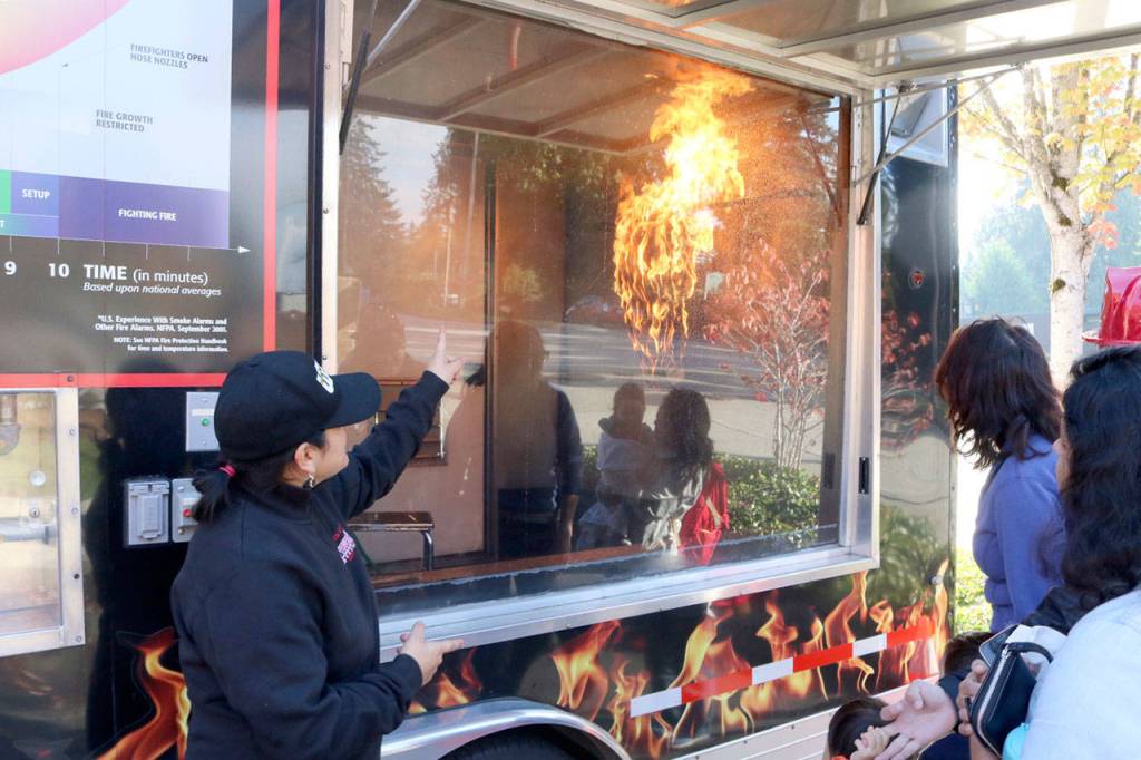 Deputy Washington State Fire Marshal Lysandra Davis, left, explains the benefits of a home sprinkler system during a demonstration of the sprinkler response time. Evan Pappas/Staff Photo
