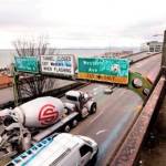 A woman takes a photo toward Elliott Bay as Alaskan Way Viaduct traffic rolls past her below ahead of an upcoming closure of the roadway, in Seattle. (AP Photo/Elaine Thompson)