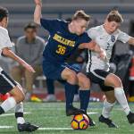 Bellevue Wolverines junior midfielder Ryan Tobin, center, battles to keep control of the ball while Lake Washingtons Dominic Koester, right, tries to take the ball away. Bellevue defeated Lake Washington 1-0 on March 21 in Bellevue. Photo courtesy of Patrick Krohn/Patrick Krohn Photography