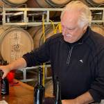 In this September 2019 photo, George Kirkish, owner and founder of Palouse Winery on Vashon-Maury Island, pours a glass of wine for Lori Coots during tasting room hours. (Kevin Opsahl/Sound Publishing)