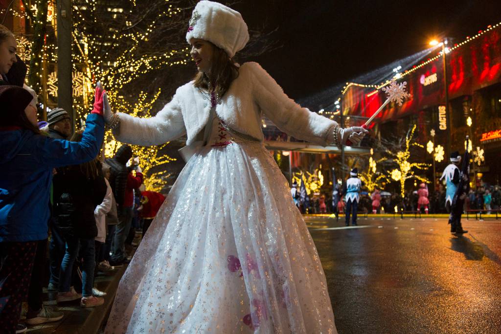 A performer gives high-fives to children standing among the crowd of people. Ashley Hiruko/staff photo