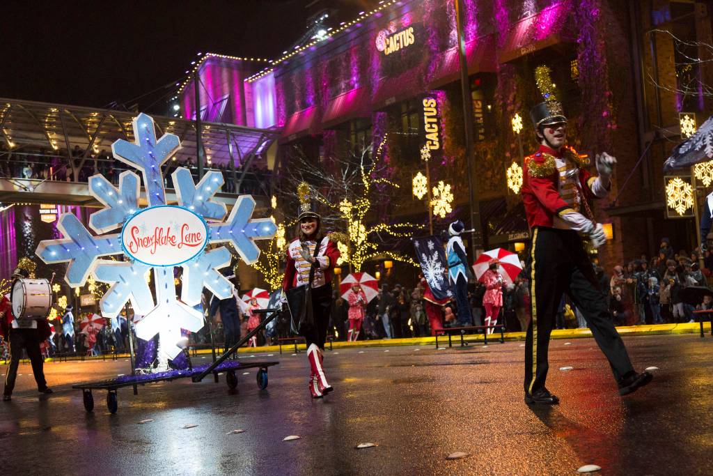 Ashley Hiruko/staff photos                                Above, a performer gives high-fives to children standing among the crowd of people.                                 Left, a large snowflake, pulled along the route, marks the beginning of the parade.