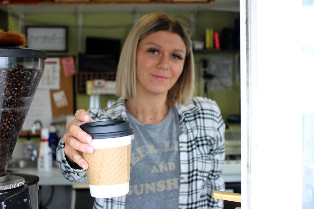 Mitchell Atencio/Staff Photo                                Above, Laura French hands a customer a drink at Megans Coffee Corner in Bellevue on Feb. 25. Below, the menu and walk-up window at Megans Coffee Corner.