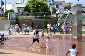 Families splash and play in the water at at Federal Ways Town Square Park to cool off from a previous heatwave in the region. (Sound Publishing file photo)