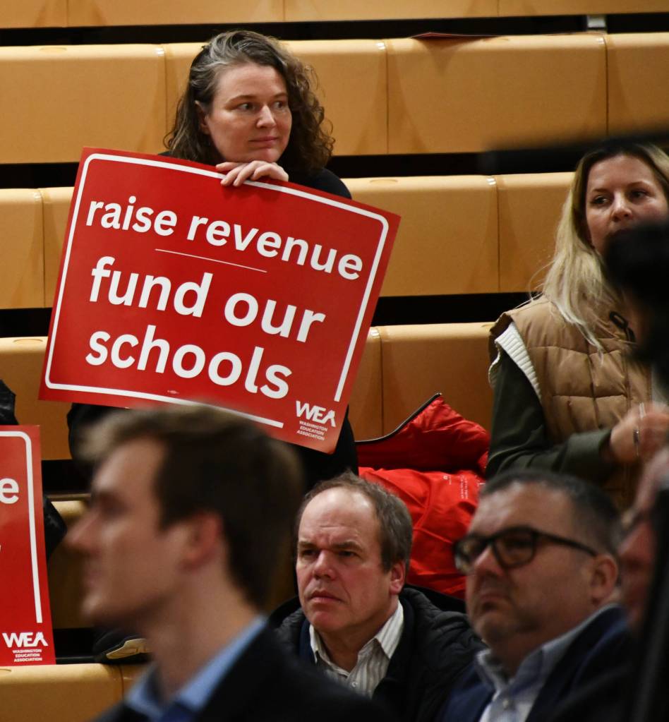 An attendee displays a sign at the School Funding Crisis regional town hall on Jan. 7 at Newport High School in Bellevue. Andy Nystrom/ staff photo